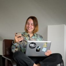 Eine junge Frau mit einem Handy und einem Laptop. 