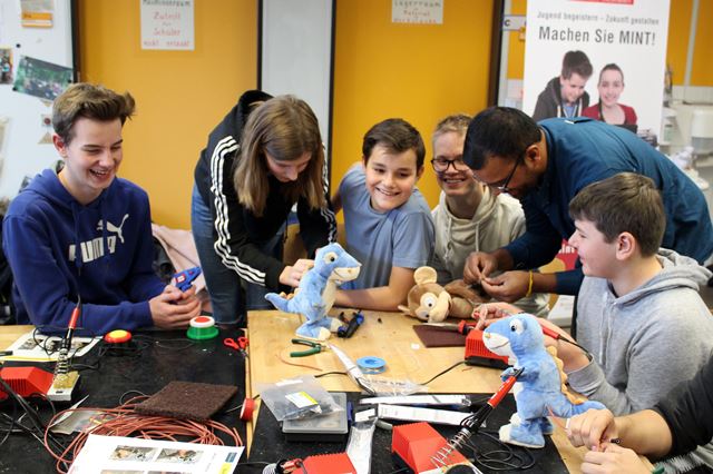 Eine Gruppe von Schüler:innen baut gemeinsam an Spielzeugen in Form eines Dinos. 