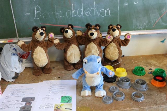 Eine Gruppe Spielzeuge in Form von Teddybären und Dinos. Daneben liegt eine Anleitung zum Zusammenbauen.