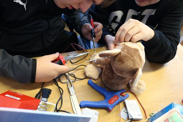 Zwei Schüler:innen löten an einem Spielzeug.