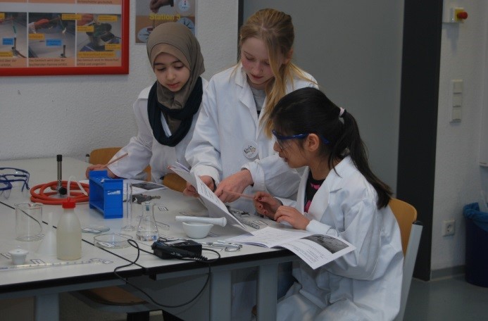 A group of three girls conducts an experiment.
