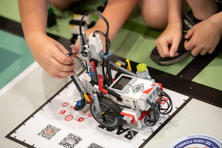 The picture shows a Lego Mindstorm robot on the starting position of the competition mat.