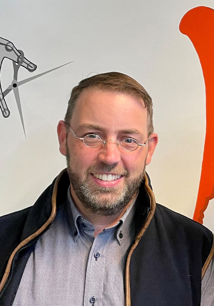 The photo shows Claas Niehues, a man with short hair, a beard and glasses, smiling at the camera. Claas Niehues is the MSB's new zdi country coordinator.