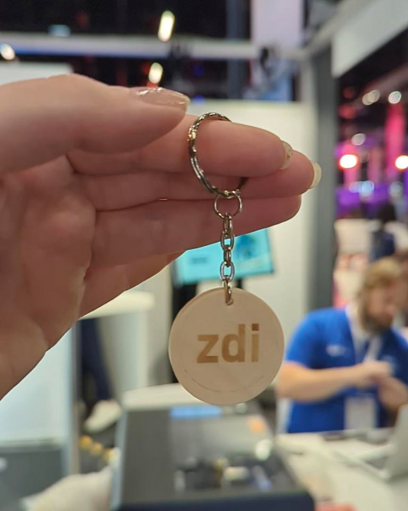 The photo shows a round wooden keychain with zdi written on it.