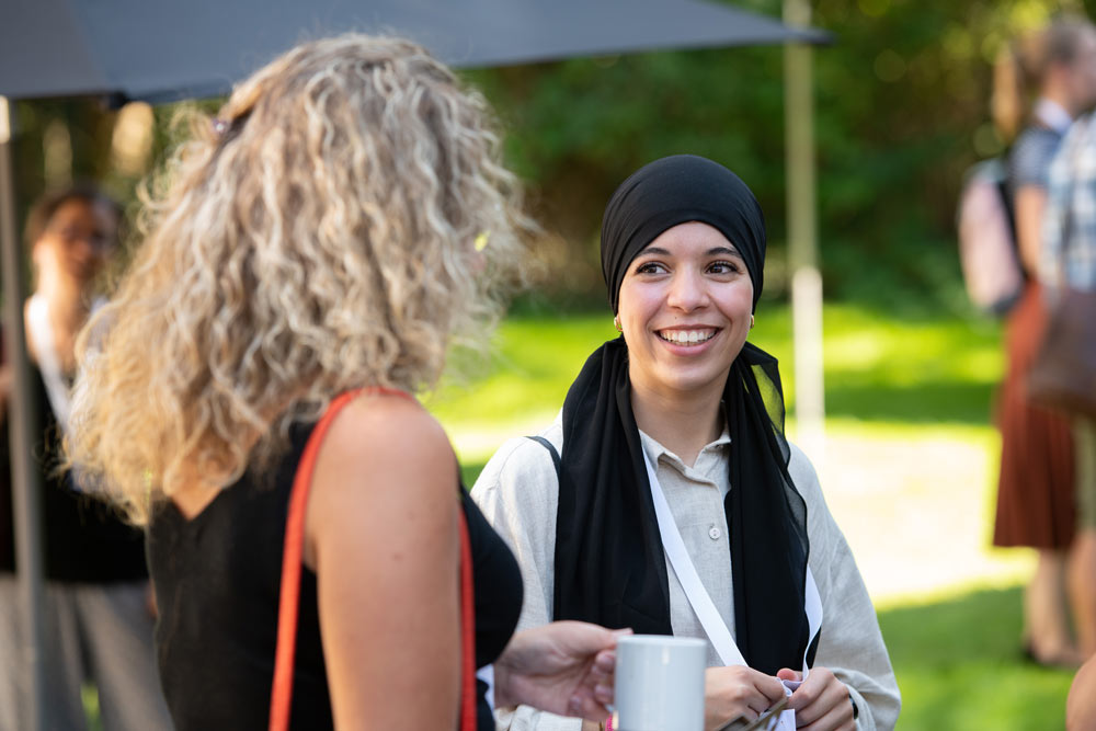 Eine Frau, die einen Hijab trägt, spricht mit einer anderen Frau.
