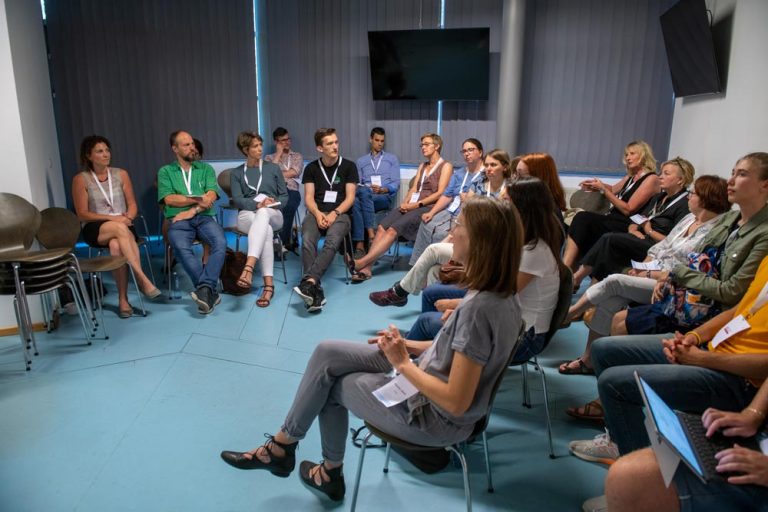 A group of people sit on chairs in a room.