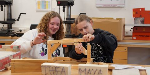 Two girls work on a wooden structure at the zdi girls camp.