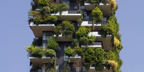Ein modernes Hochhaus. Die Balkone sind üppig grün bepflanzt, so dass das Haus fast wie ein grüner Quader, der in den Himmel reicht, ausssieht.