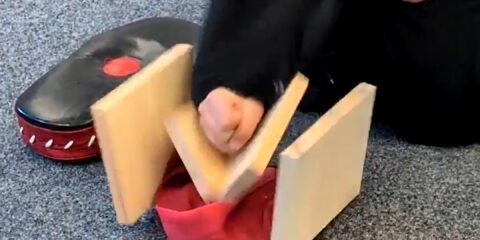 Mädchen schlägt auf ein Holzbrett und zerbricht es.