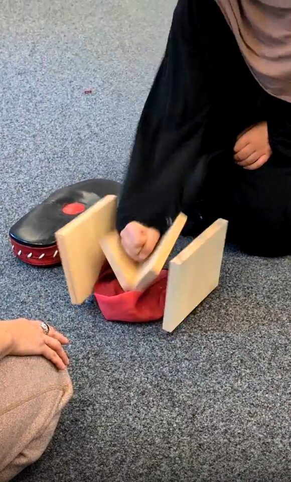 Mädchen schlägt auf ein Holzbrett und zerbricht es.