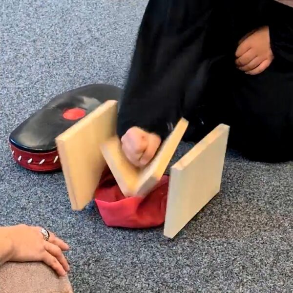 Mädchen schlägt auf ein Holzbrett und zerbricht es.